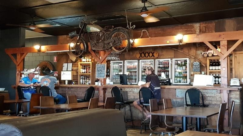Darwin to Cairns road trip Rustic outback pub bar with XXXX beer signage, vintage motorcycle décor and patrons seated at the counter at Barkly Homestead Bar