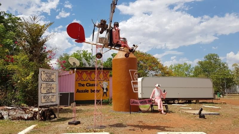 Darwin to Cairns road trip Quirky outback display at Larrimah Wayside Inn featuring pink mannequins, a mock helicopter, and giant beer can in the Northern Territory