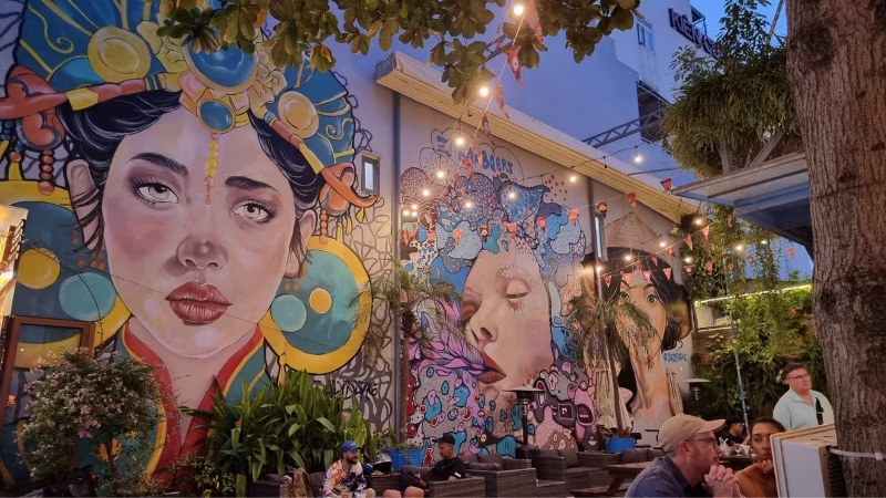 Long Stays in Vietnam People dining at an outdoor bar with large street art murals in Da Nang, Vietnam during the evening