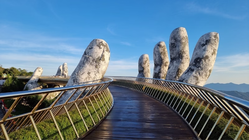 Long Stays in Vietnam Golden Bridge in Ba Na Hills near Da Nang, Vietnam with giant stone hands holding the curved pedestrian walkway