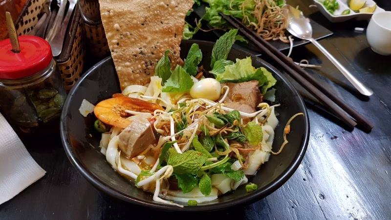 Long Stays in Vietnam Bowl of mì Quảng with pork, quail egg, fresh herbs and rice noodles at a local eatery in Da Nang, Vietnam