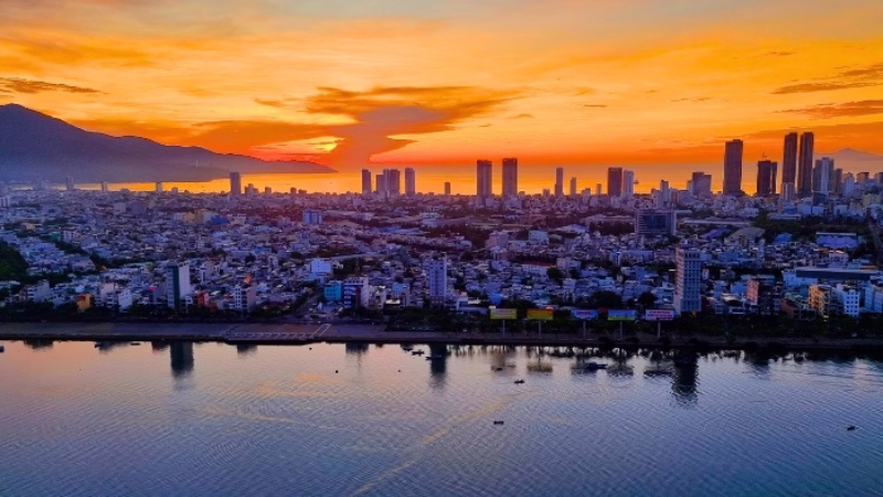 Long Stays in Vietnam Skyline of Da Nang, Vietnam at sunrise with city buildings, mountains and the Han River reflecting golden morning light
