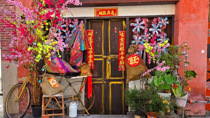 Traditional Chinese doorway in George Town, Penang, decorated with red banners, paper flowers, lanterns and a vintage bicycle