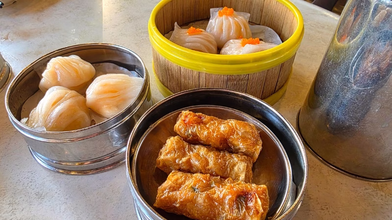 Assorted dim sum including har gow and fried bean curd rolls served in traditional steam baskets at a Chinese restaurant in Penang