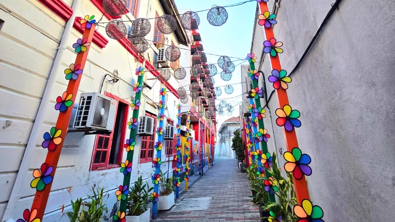 Narrow alleyway in George Town, Penang, decorated with colourful pinwheels, hanging lanterns and vibrant murals.