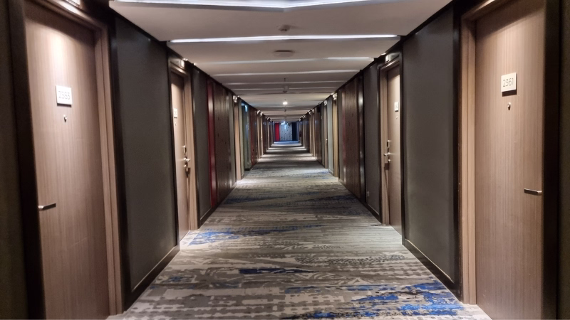 Internet When Travelling Long hotel corridor with patterned carpet and closed room doors in a modern high-rise accommodation block.