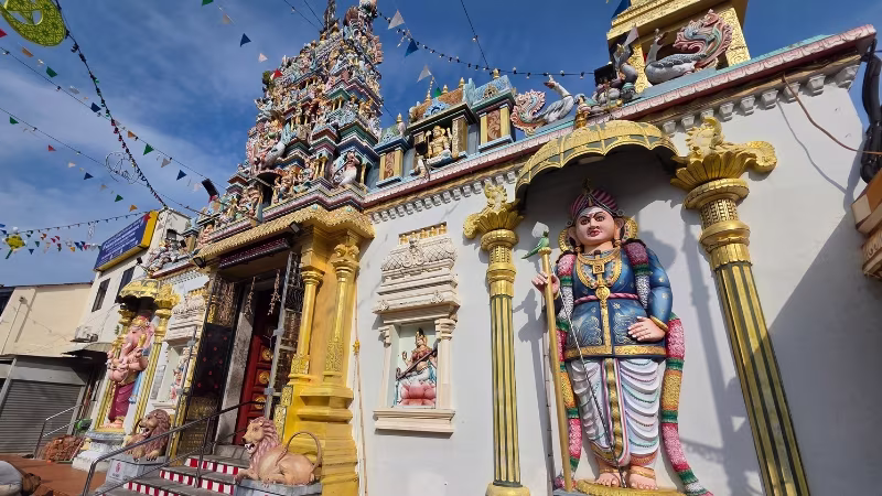 Colourful facade of Sri Mahamariamman Temple in George Town, Penang, featuring intricate Hindu statues, religious carvings and vibrant decorative details under a clear blue sky
